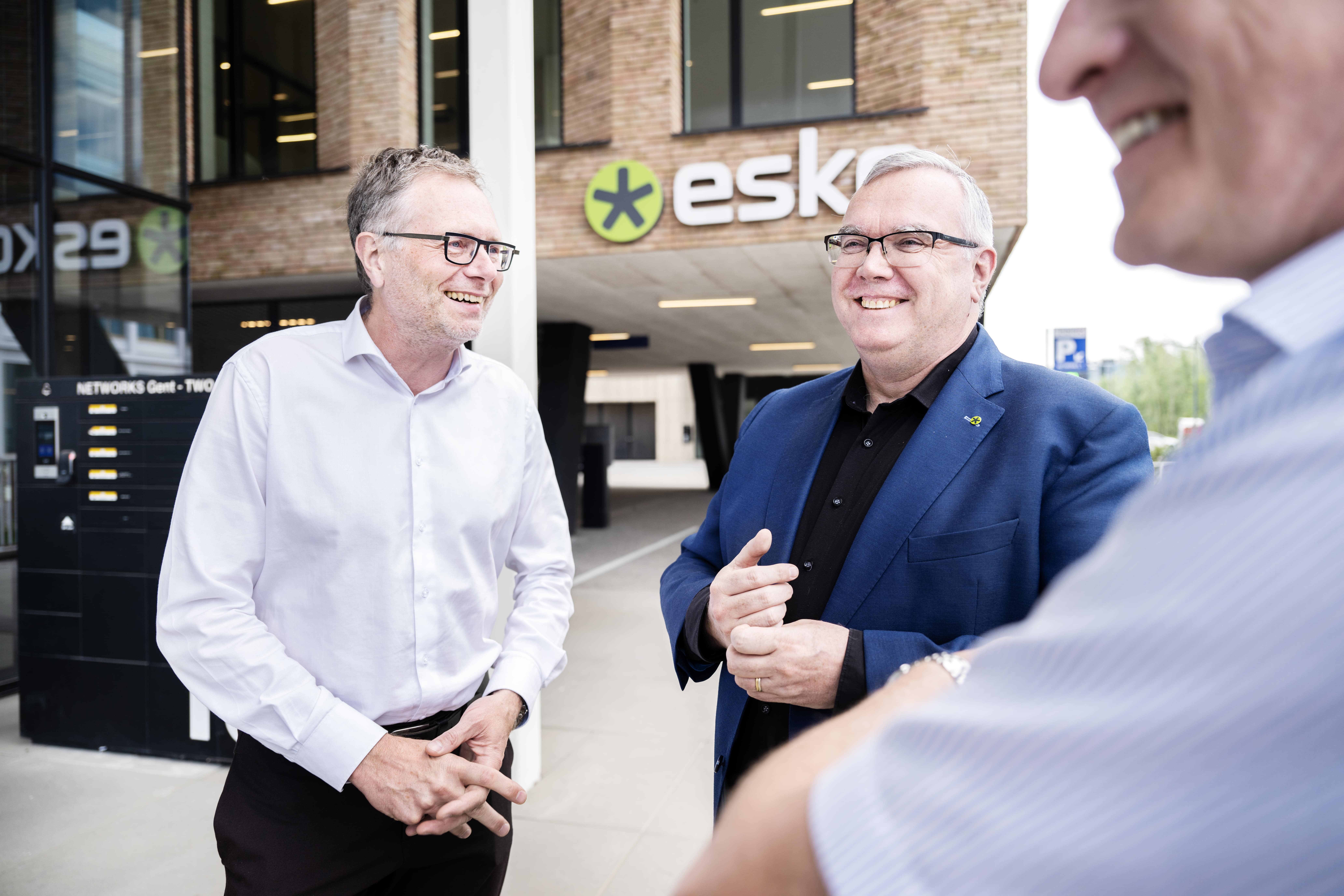 Three people talking outside an Esko office building, with visible company logo and modern architecture in the background