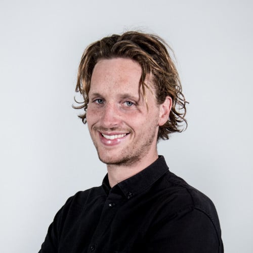 Raoul Mancke with wavy brown hair wearing a black shirt against a plain background