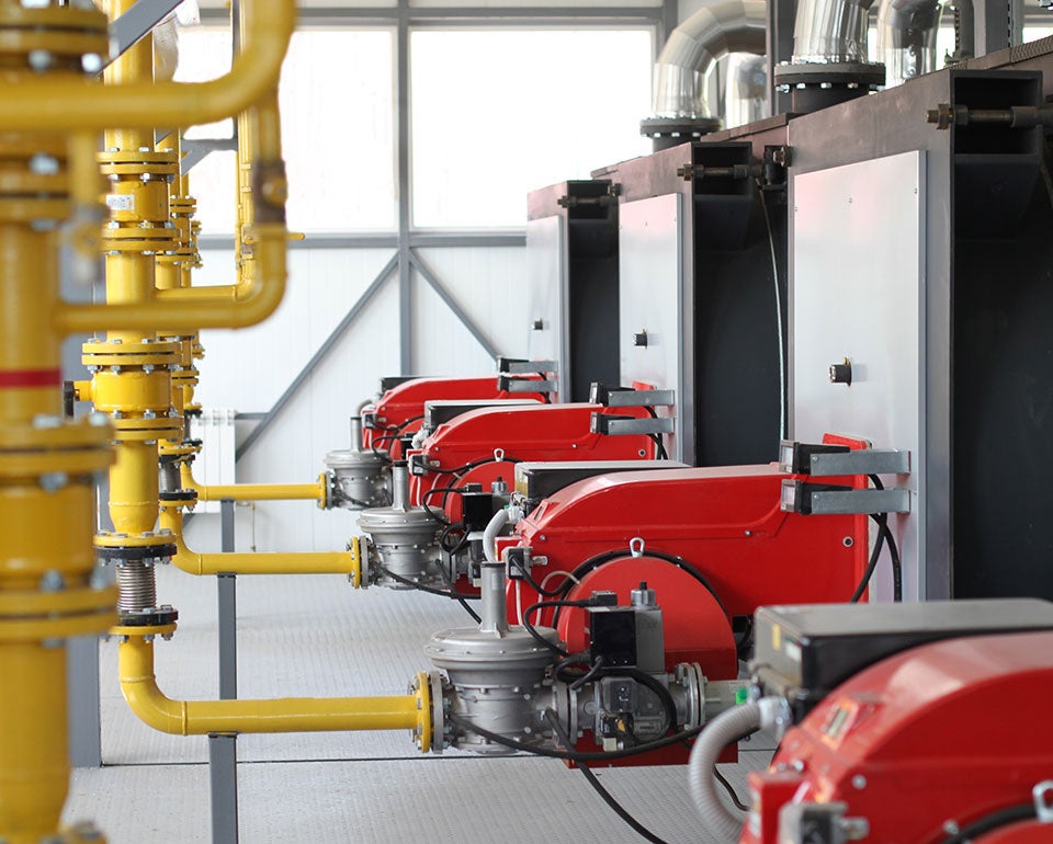 Industrial gas burners with yellow piping in a mechanical room, showcasing modern heating equipment installation