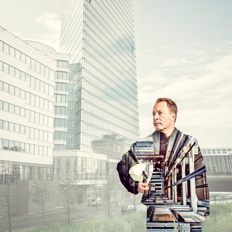 Man holding a hard hat with a transparent architecture overlay, showcasing a cityscape featuring tall office buildings, reflecting modern urban development and construction themes