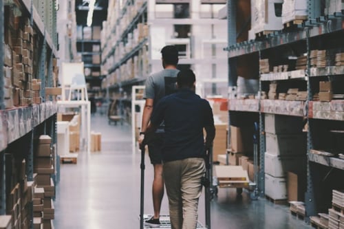 Två personer går runt i ett stort lager.