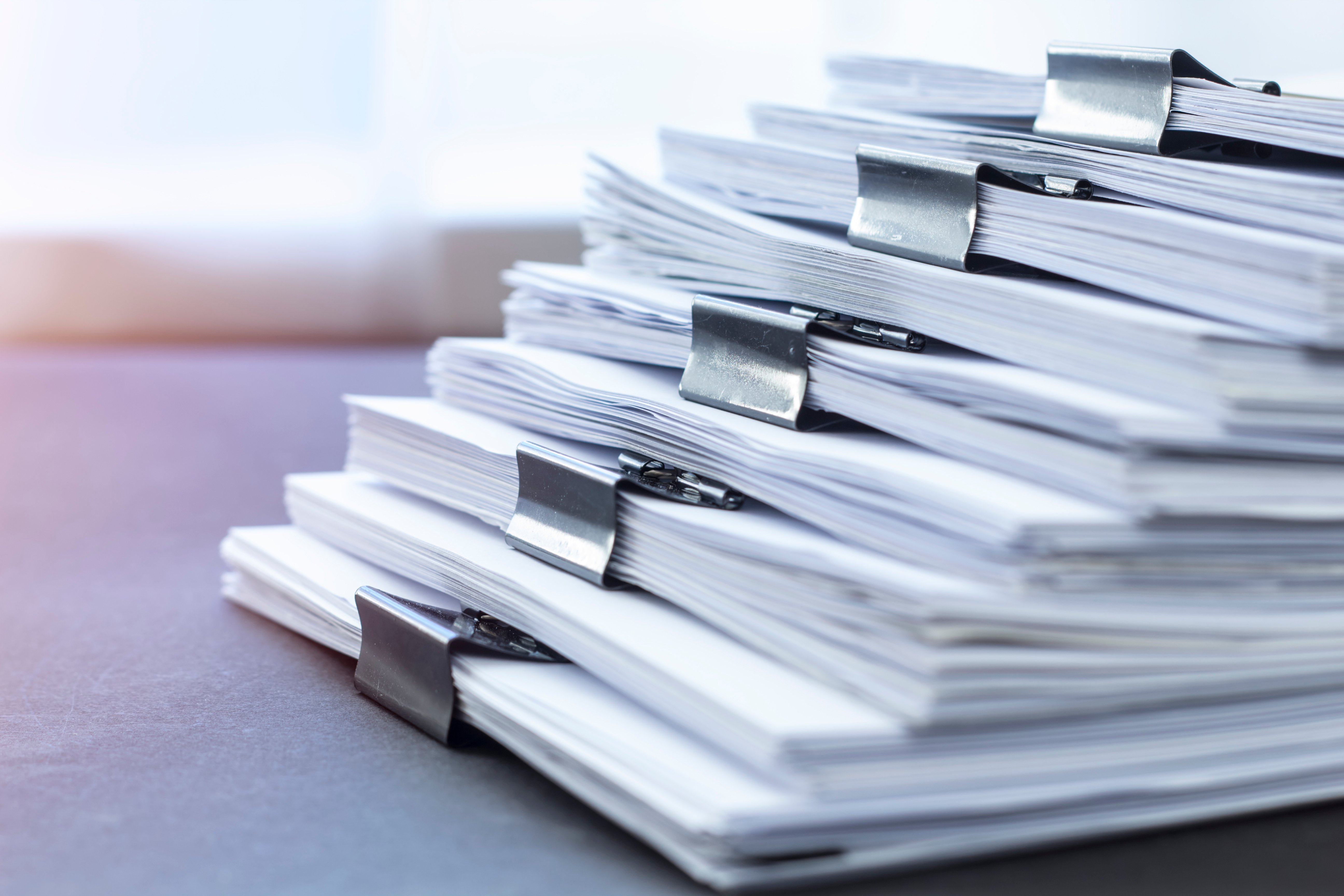 Stack of white paper documents clipped together on a desk.