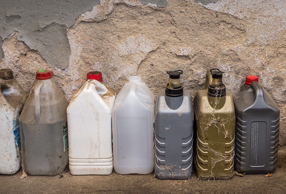 Flera dunkar med kemikalier som står på golven i en verkstad. 