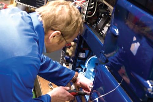 Technician repairing machinery in a workshop, focused on electrical components and wiring